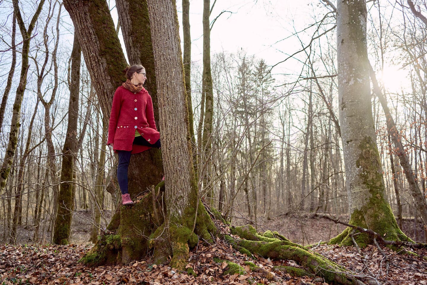 Frau lehnt an Baum im Herbstwald.