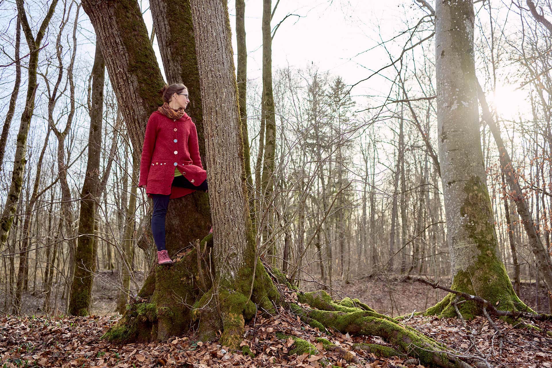 Frau lehnt an Baum im Herbstwald.